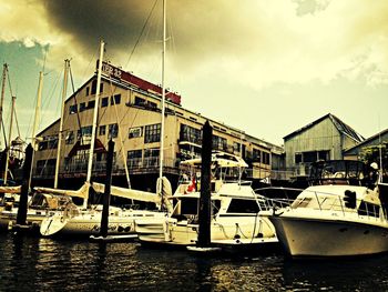 Boats in harbor against cloudy sky