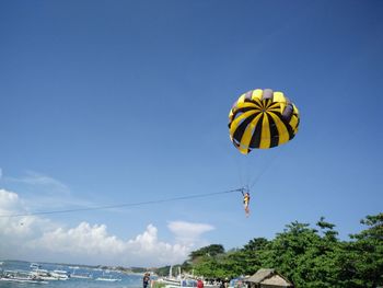 Low angle view of person parasailing over beach against sky