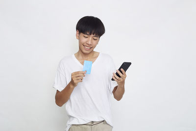 Young man using smart phone against white background