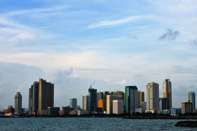 Modern buildings by sea against sky