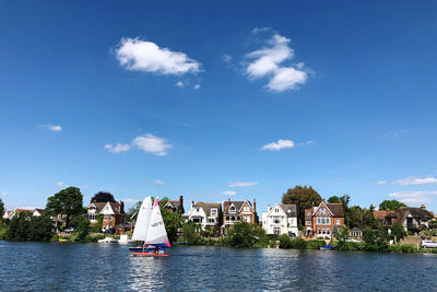 Sailboats in city by buildings against sky