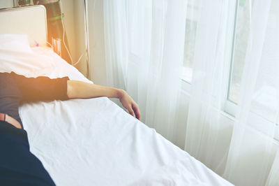 Midsection of man relaxing on bed at hospital