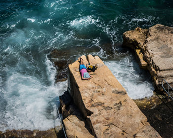 High angle view of man surfing on rock in sea