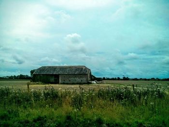 View of grassy field against cloudy sky