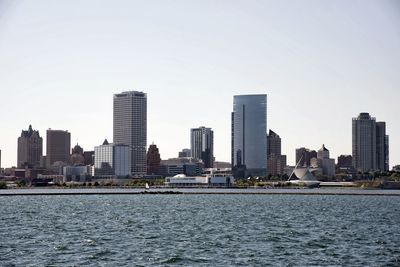 Sea by modern buildings against sky in city