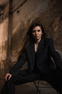 Portrait of woman sitting against wall