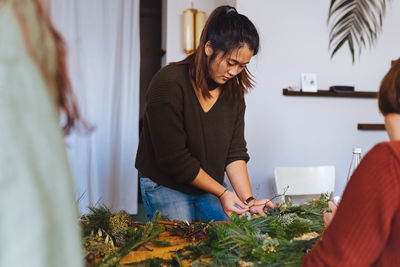 Young woman holding plant decoration at home during christmas