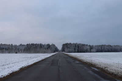 Road amidst snow covered trees against sky