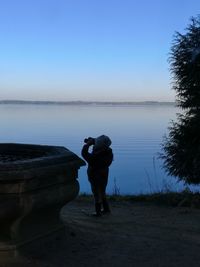 Full length of man photographing lake against sky