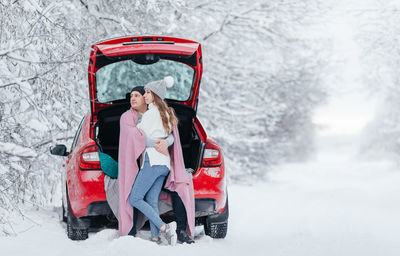 Side view of a woman on snow covered car