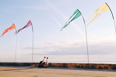 Low angle view of people walking on shore against sky