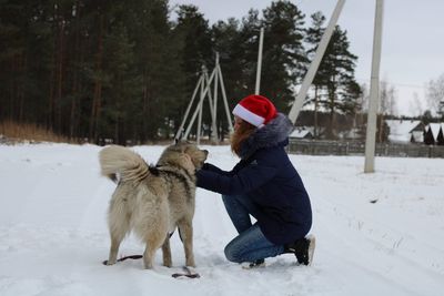 Side view of woman playing with dog in snow