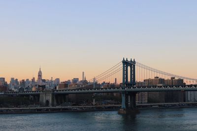 Suspension bridge over river at sunset