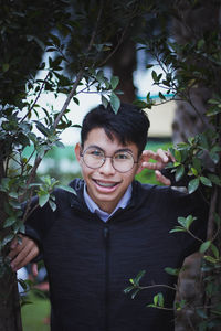 Portrait of smiling teenage boy with braces standing by plants