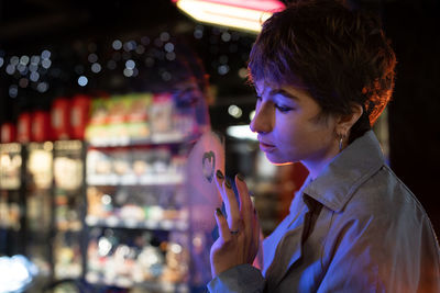 Thoughtful melancholic woman draw heart on steamy wet window think of boyfriend, love relationship