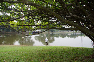 Mid distance view of senior man standing by lake at public park