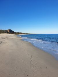 Scenic view of beach against clear blue sky