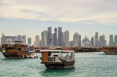 Boat in sea by modern buildings in city against sky