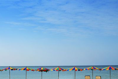 Multi colored deck chairs on beach against blue sky