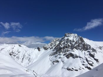 Scenic view of snow covered mountains against blue sky