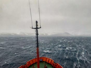 Scenic view of boat in sea against sky during winter