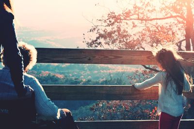 Senior woman and girl at railing during sunset