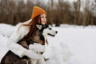 Portrait of woman with dog on snow covered field