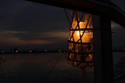 Reflection of illuminated lamp in lake at sunset