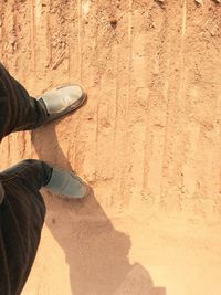 Low section of man standing on sand