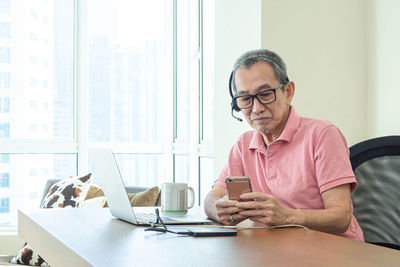 Man using mobile phone while sitting on table