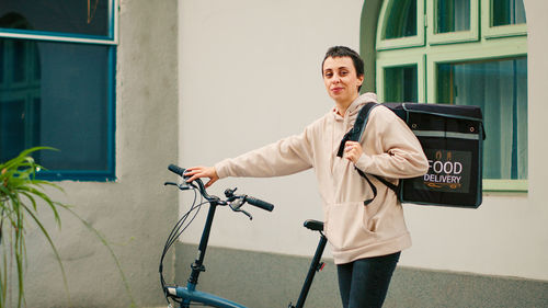 Portrait of young woman standing against wall