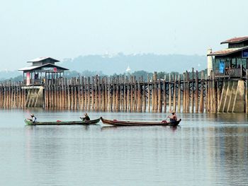 People on wooden post by sea against sky