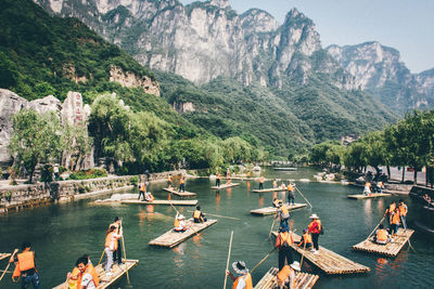People on river by mountains