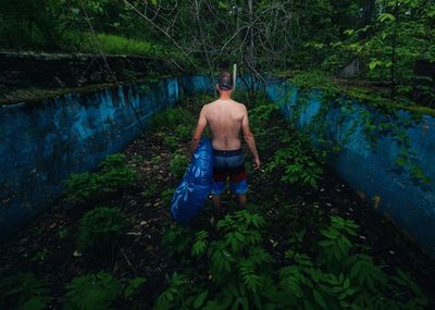 Full length of shirtless man standing on tree