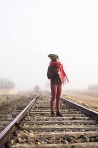 Full length of woman standing on railroad tracks against clear sky