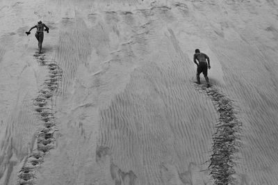 Rear view of man and woman running up a dune 