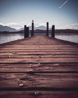 Surface level of wooden pier over sea against sky