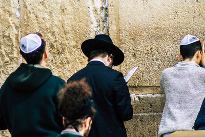 Rear view of people standing against wall