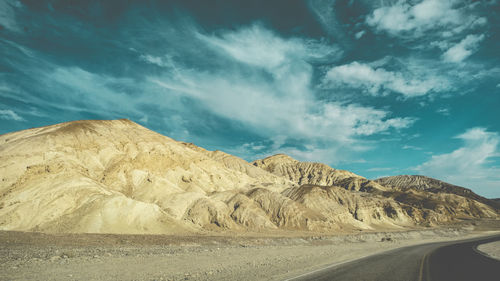 Scenic view of road by mountains against sky