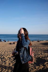 Woman standing on beach against clear sky