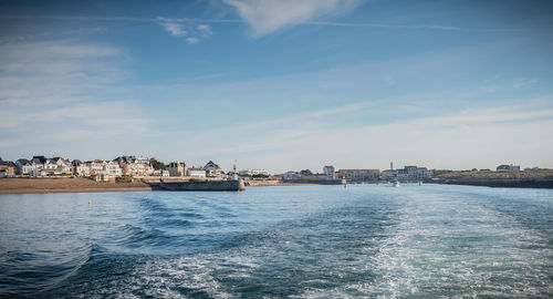 Sea by buildings in city against sky