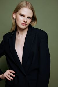 Portrait of young woman standing against gray background