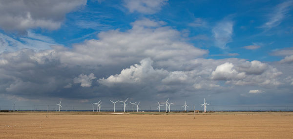 Wind turbines on land against sky