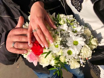 Midsection of couple holding flower bouquet