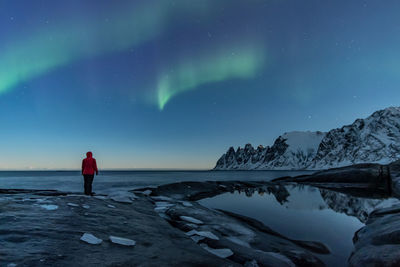 Rear view of person standing on snow against sky at night