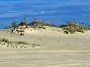 Scenic view of beach against cloudy sky