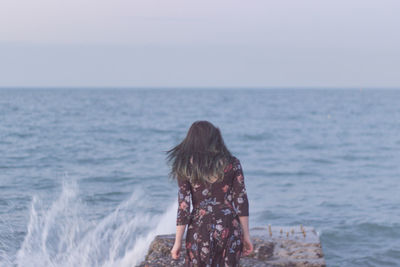 Rear view of woman on beach against sky