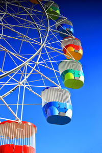 Low angle view of ferris wheel against clear blue sky