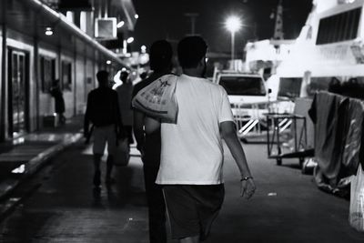 Rear view of people walking on street at night