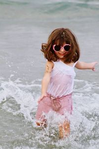 Full length of girl wearing sunglasses running in sea